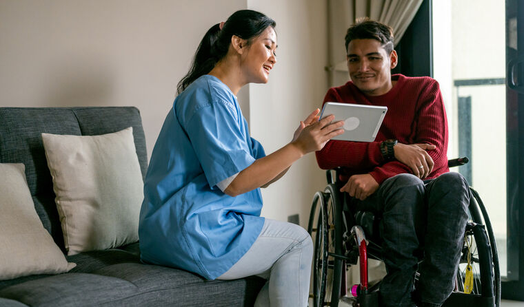 Carer supporting a person at home with a warm smile